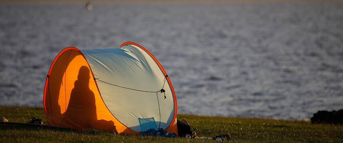 Mensch sitzt an der Nordsee in Strandmuschel, Fragen und Antworten über die Seelsorge im Kirchenkreis Nordfriesland